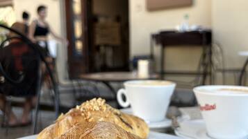A croissant on a plate with a cup of coffee in the background.