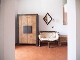 Une pièce comprenant une armoire en bois, un miroir, un fauteuil rembourré et un petit meuble.