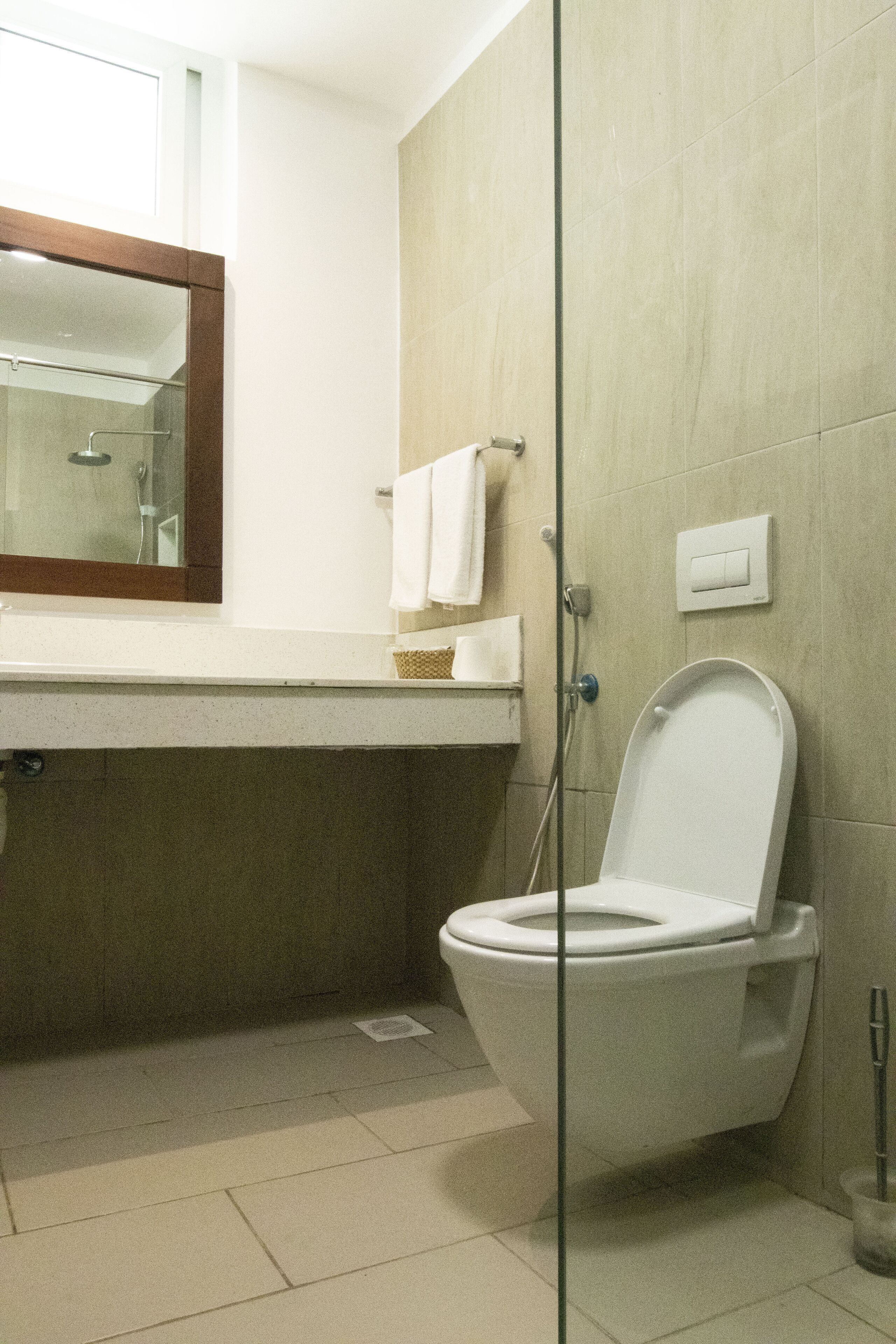 Een badkamer met een toilet, een wastafel, een spiegel en een douche.