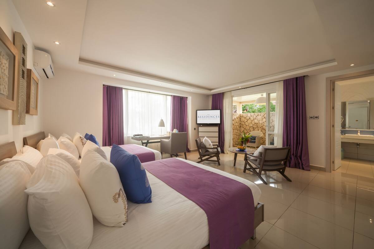 Una habitación de hotel con dos camas, un escritorio, una silla, un televisor y un baño.