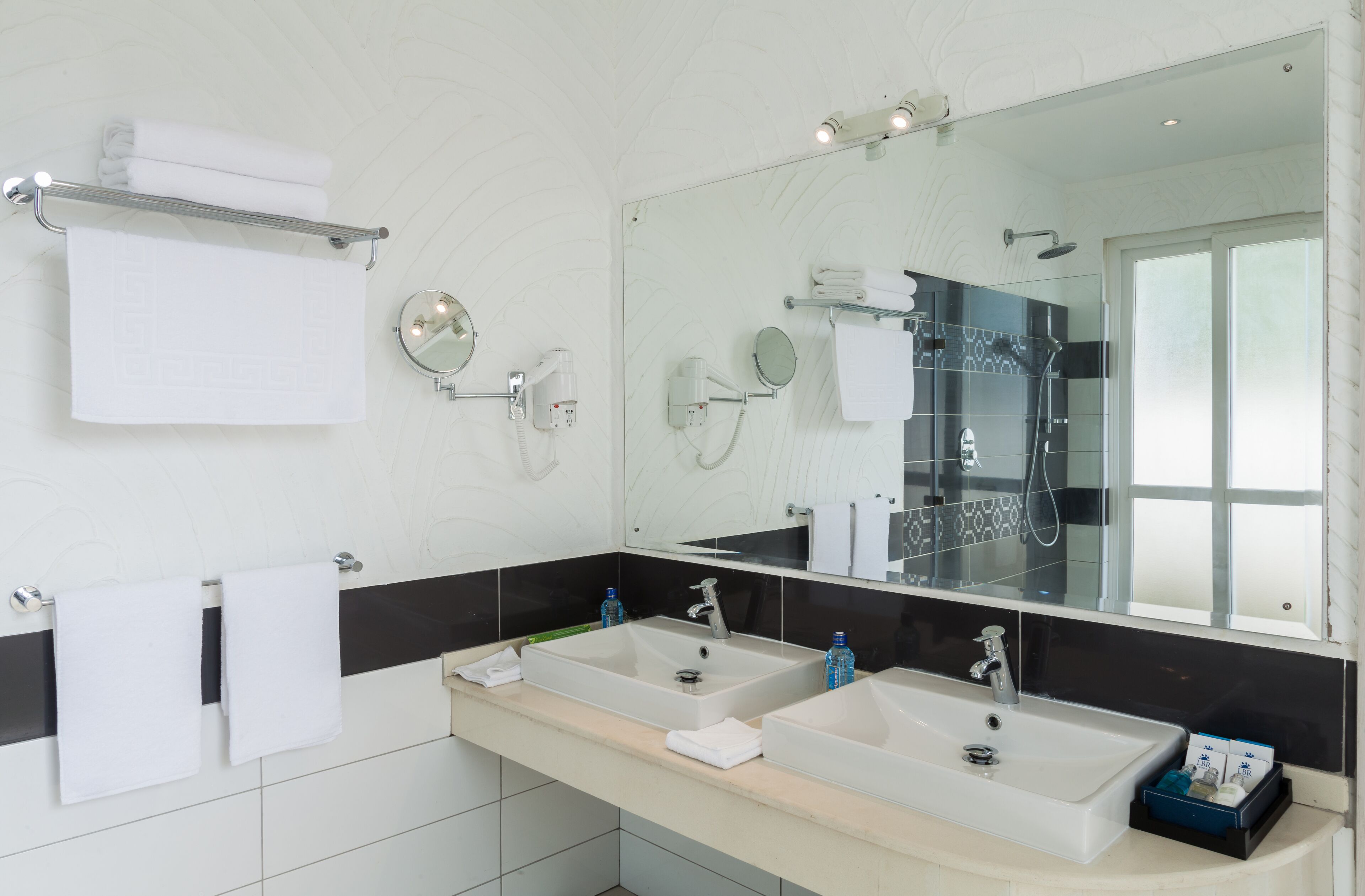 Un baño moderno con dos lavabos, un espejo grande y un perchero para toallas.