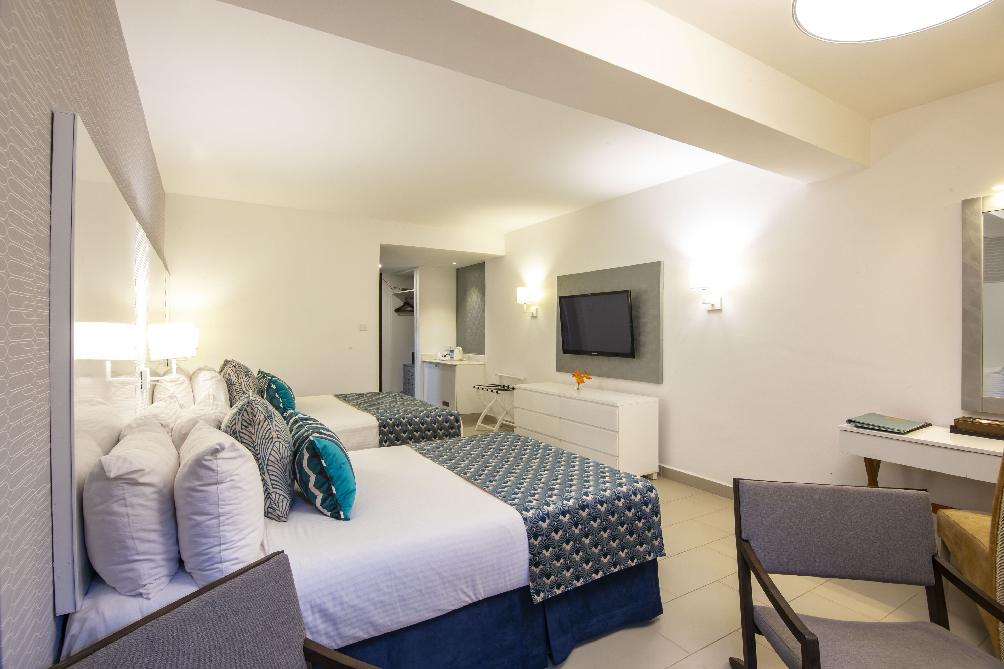 Een hotelkamer met een bed, bureau, stoel, televisie en spiegel.