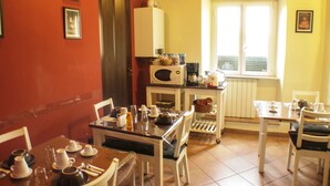 A dining area with a table set for four, chairs, a microwave, and a window with blinds. - Sixtythree Guesthouse (Rome)