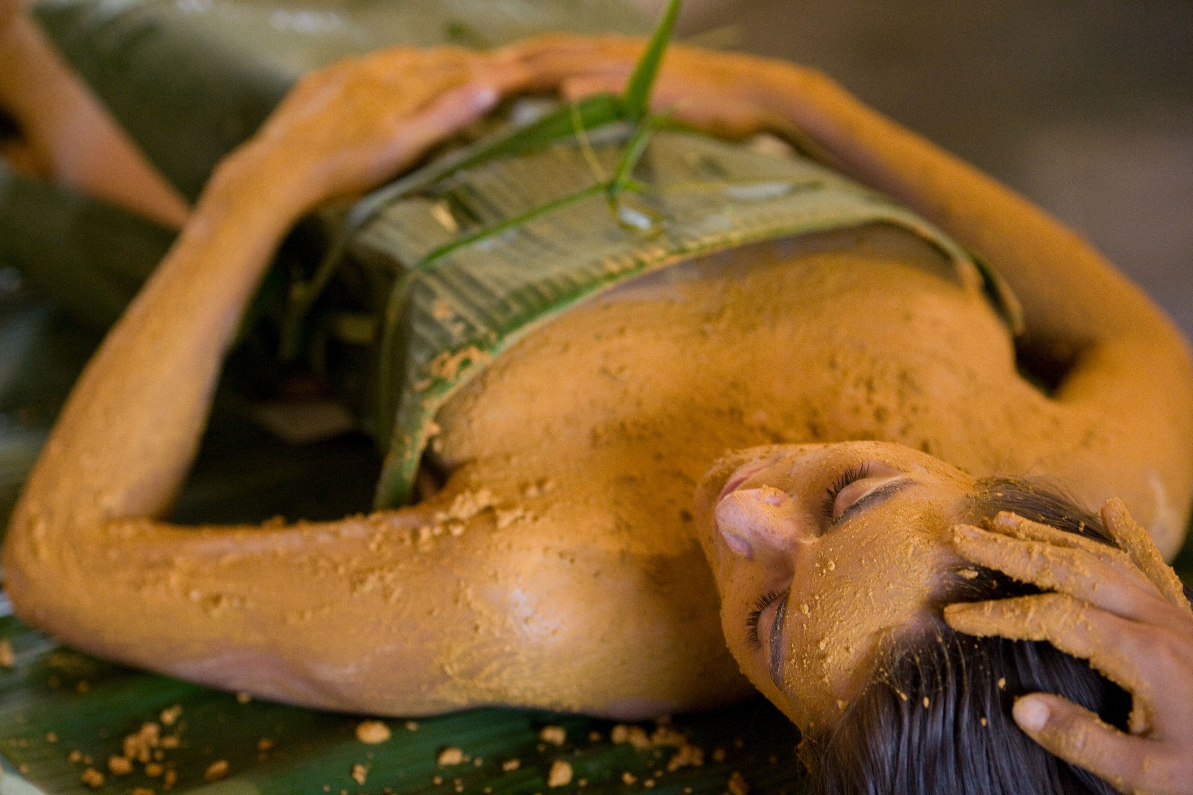 A person lying on a bed covered with a blanket.