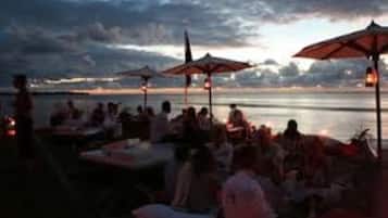 Un restaurante en la playa con terraza y sombrillas.