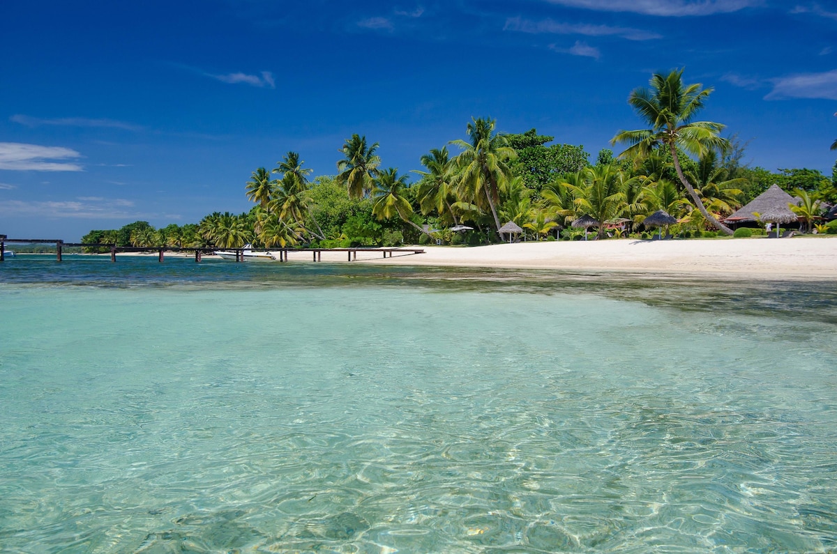 Beach with turquoise water and thatched villas at Princesse Bora Lodge and Spa