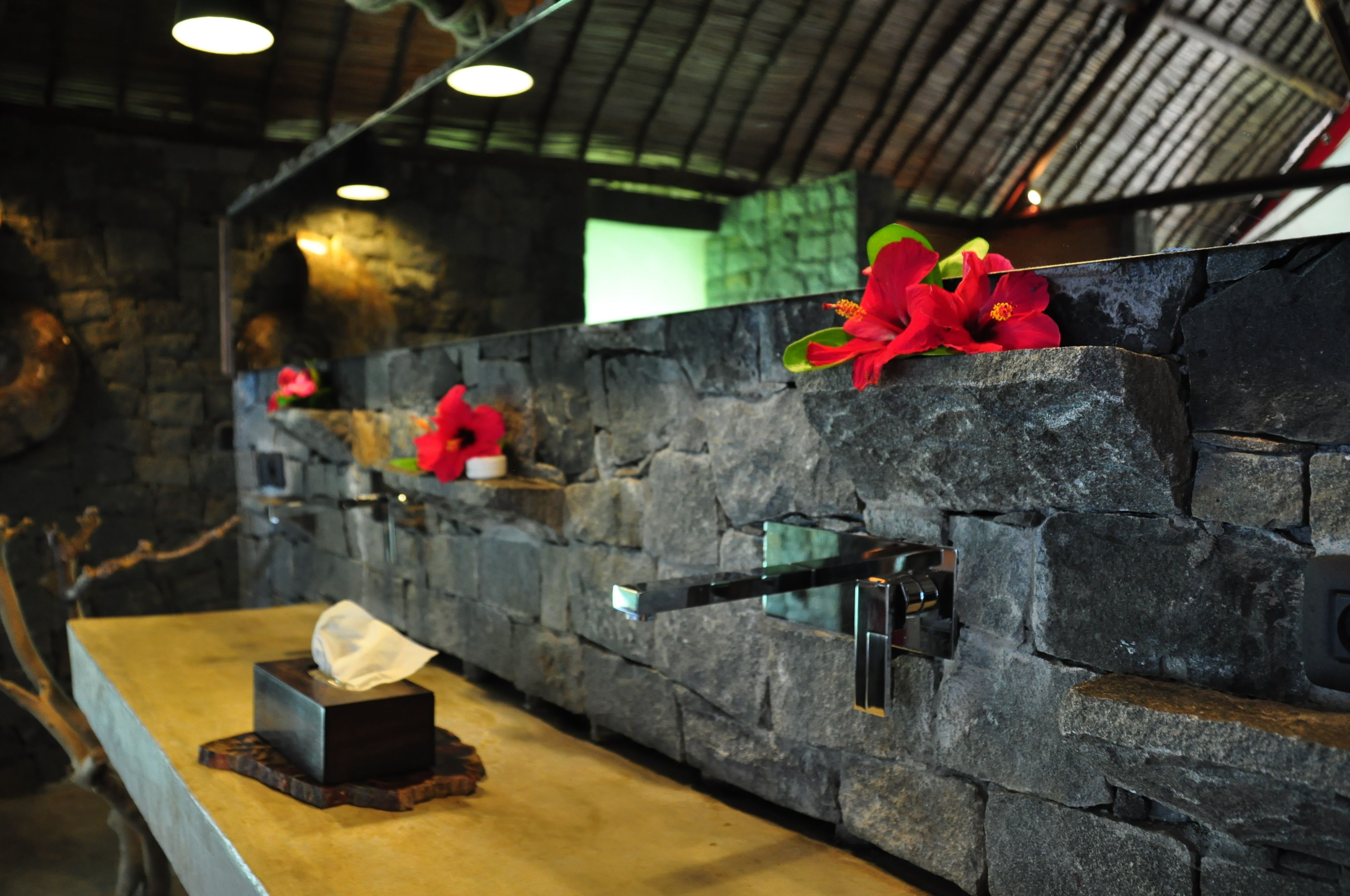 A stone wall with a sink and a tissue box.
