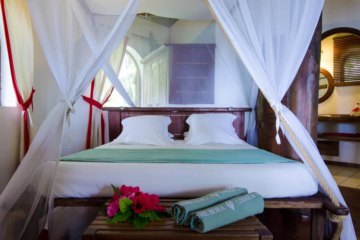 A bed with a canopy, a wooden headboard, and a green towel.