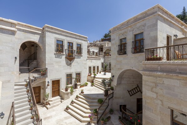 Un patio con edificios de piedra, varios balcones y plantas en macetas.