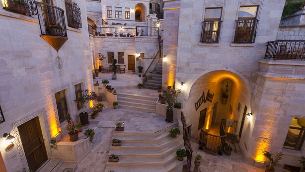 A courtyard with stone steps, potted plants, and a staircase leading to an upper level. - Magic Cave House (Ürgüp)