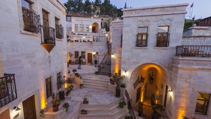 A multi-story building with stone walls, balconies with wrought iron railings, and potted plants. - Magic Cave House (Ürgüp)