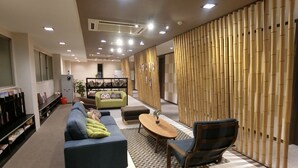 Una sala de estar moderna con sofá, sillón y mesa de centro. Hay una estantería y un panel decorativo en la pared.