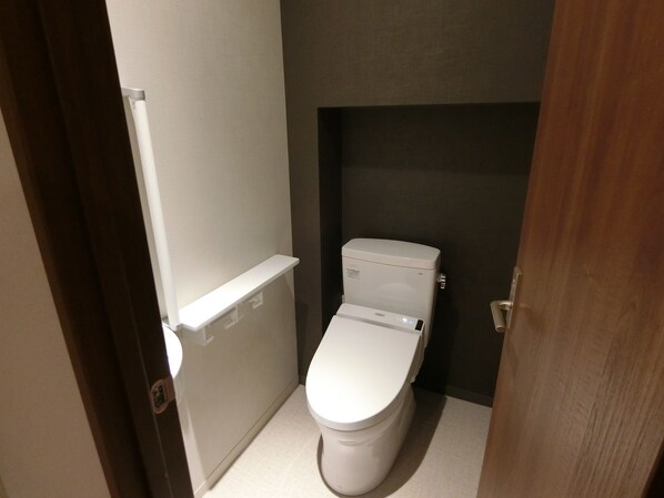 Casa de banho pequena e compacta com sanita branca, lavatório branco e um porta-toalhas.