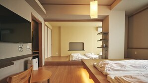 Una habitación de hotel con cama, escritorio, silla, televisor y estante.