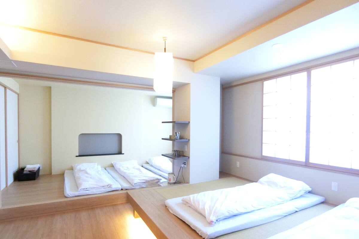 Ein Hotelzimmer mit zwei Betten, einem kleinen Schreibtisch, einem Fernseher und einem Fenster.