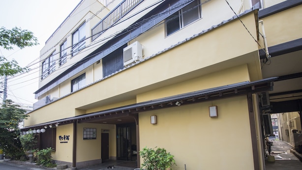 Un edificio de varios pisos con fachada amarilla, un acceso cubierto y un cartel.