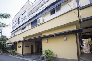 Um edifício de vários andares com fachada amarela, entrada coberta e uma placa.