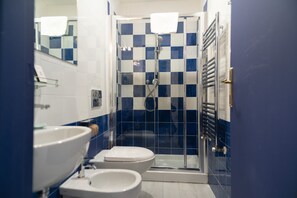 Un baño con ducha, dos inodoros y un lavabo.