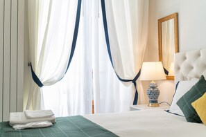Una habitación de hotel con una cama, una mesita de noche con una lámpara y cortinas translúcidas.