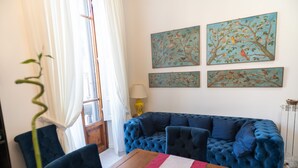 A living room with a blue sofa, a wooden coffee table, and a painting of birds on the wall. - La Residenza di Michelangelo (Florence)