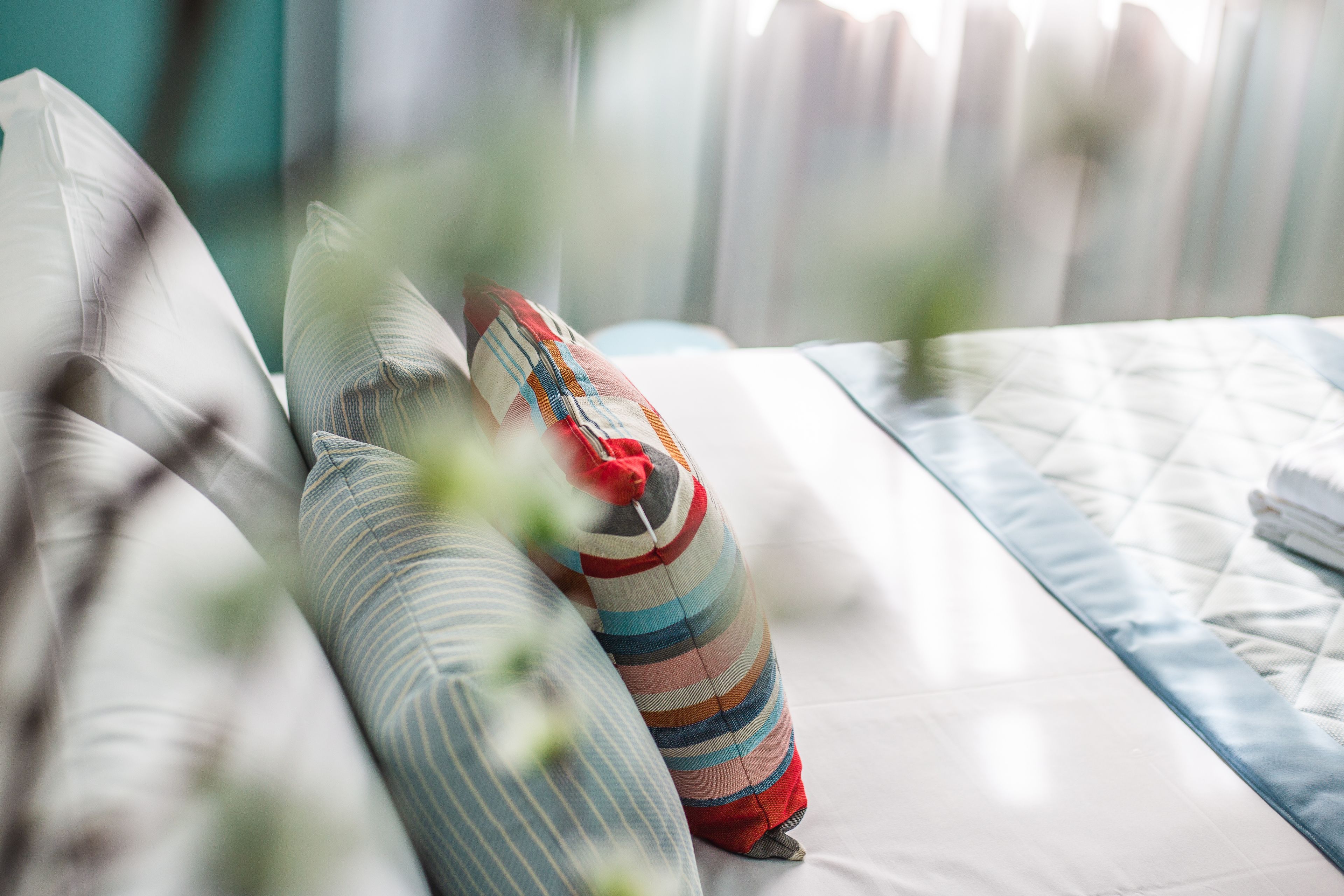 Una cama con almohadas a rayas y una colcha acolchada.