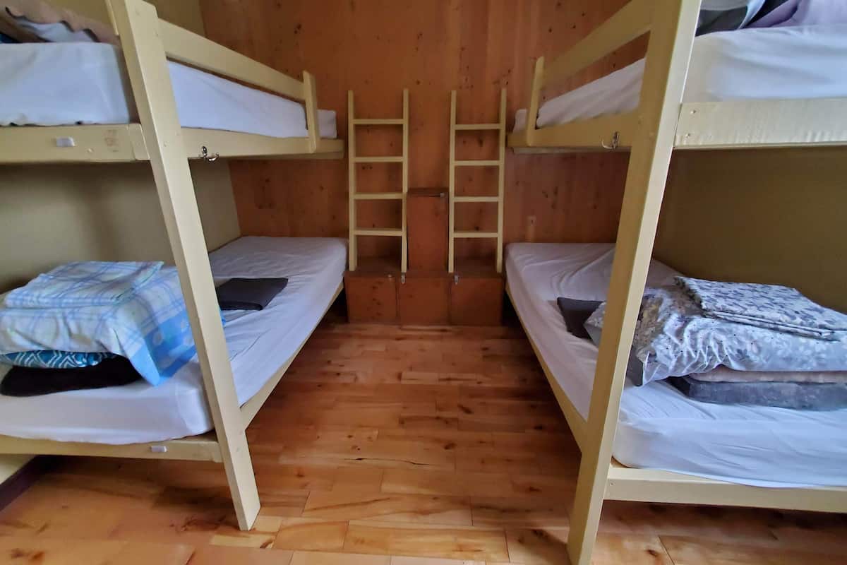 Una stanza con cuccette, pavimenti in legno e letti a castello.