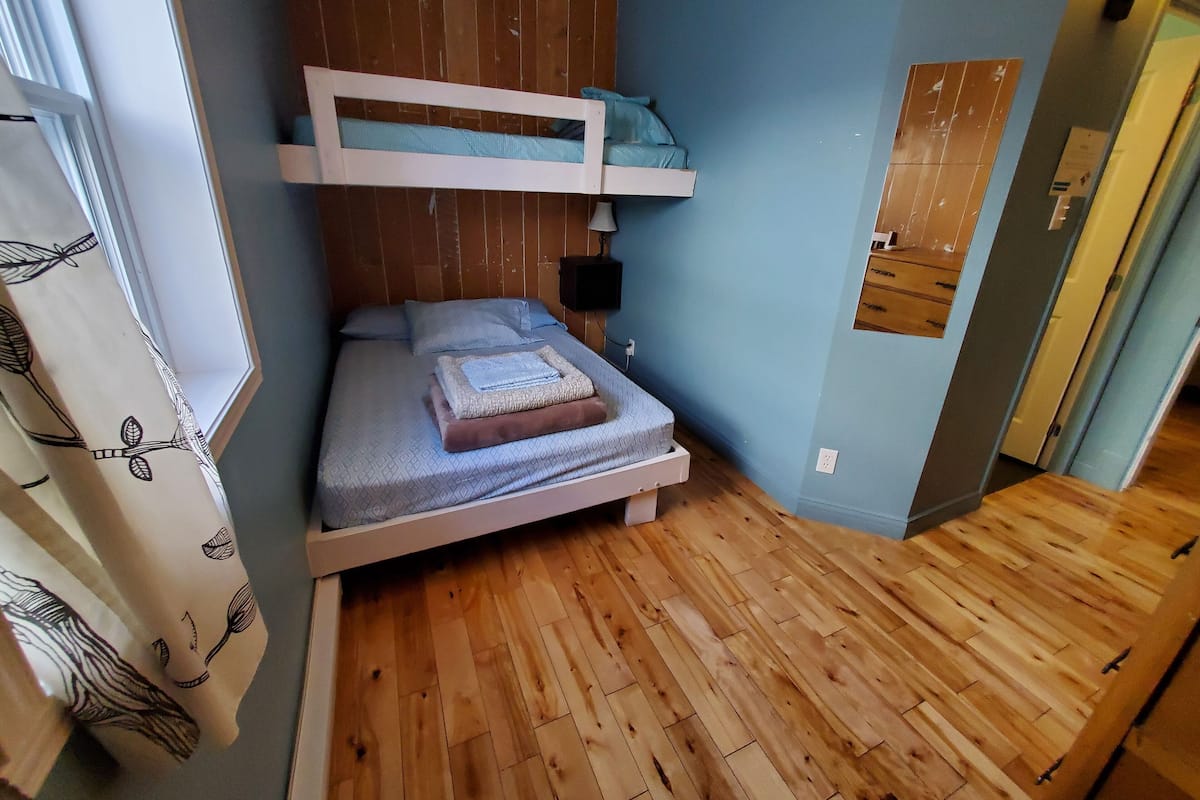 Una stanza compatta con un letto a castello, un comodino e una lampada a parete.