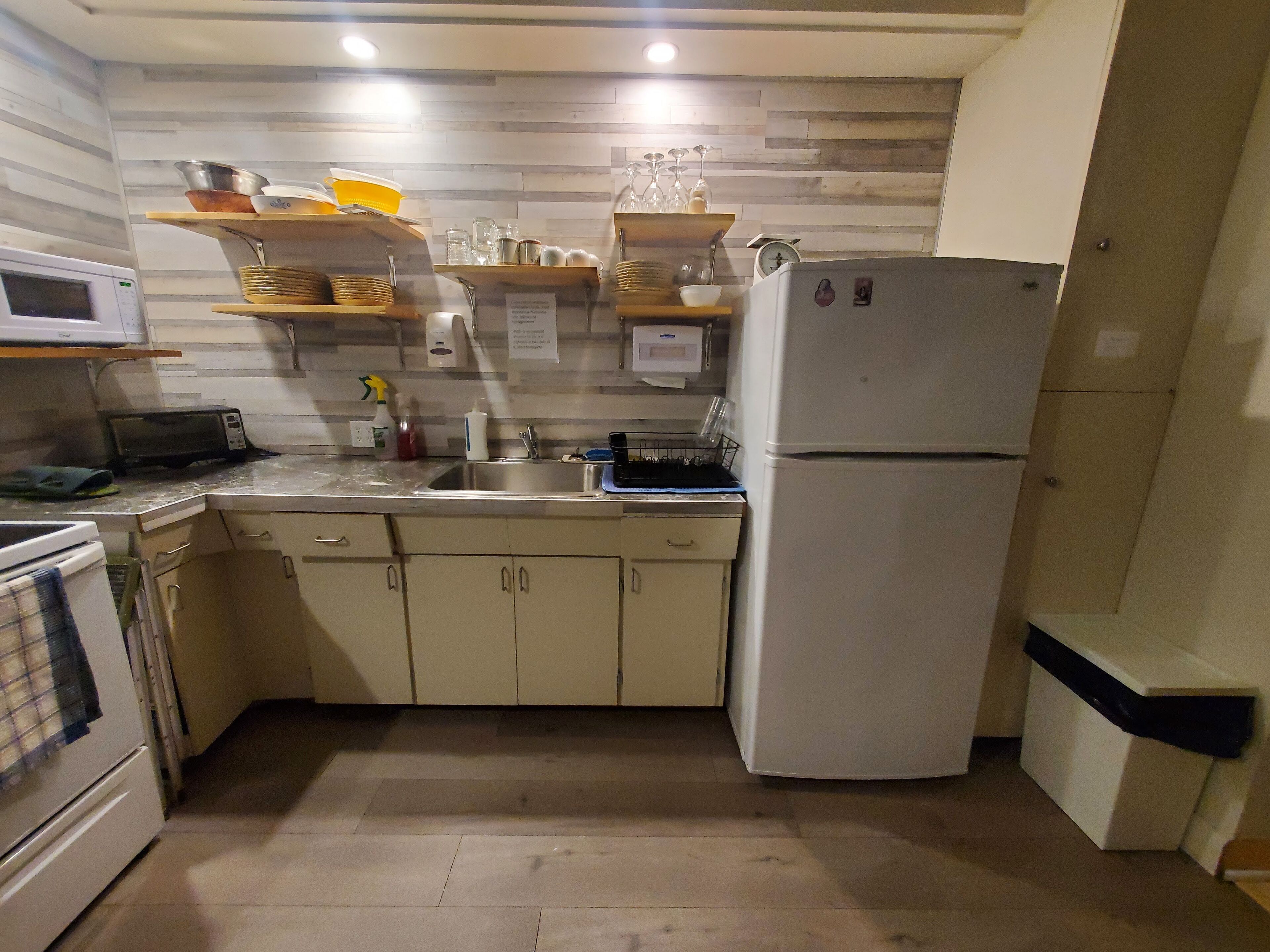 A compact kitchen with a microwave, stove, sink, and a refrigerator.