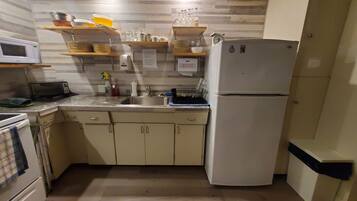 A compact kitchen with a microwave, stove, sink, and a refrigerator.