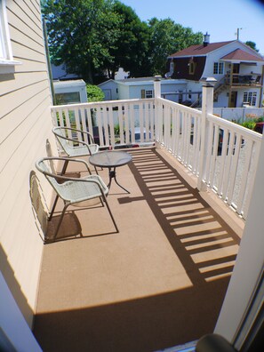 A covered balcony with a table and chairs, white railings, and a view of neighboring houses. - Auberge Jeunesse LouLou's Backpacker Hostel (Levis)