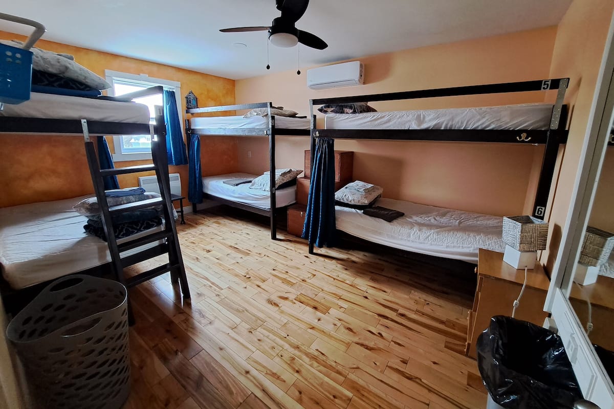 Una camera del dormitorio con letti a castello, una ventola a soffitto, un condizionatore d'aria e un pavimento in legno.