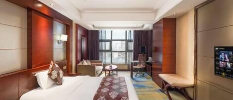 A hotel room with a large bed, a desk, a chair, and a television.