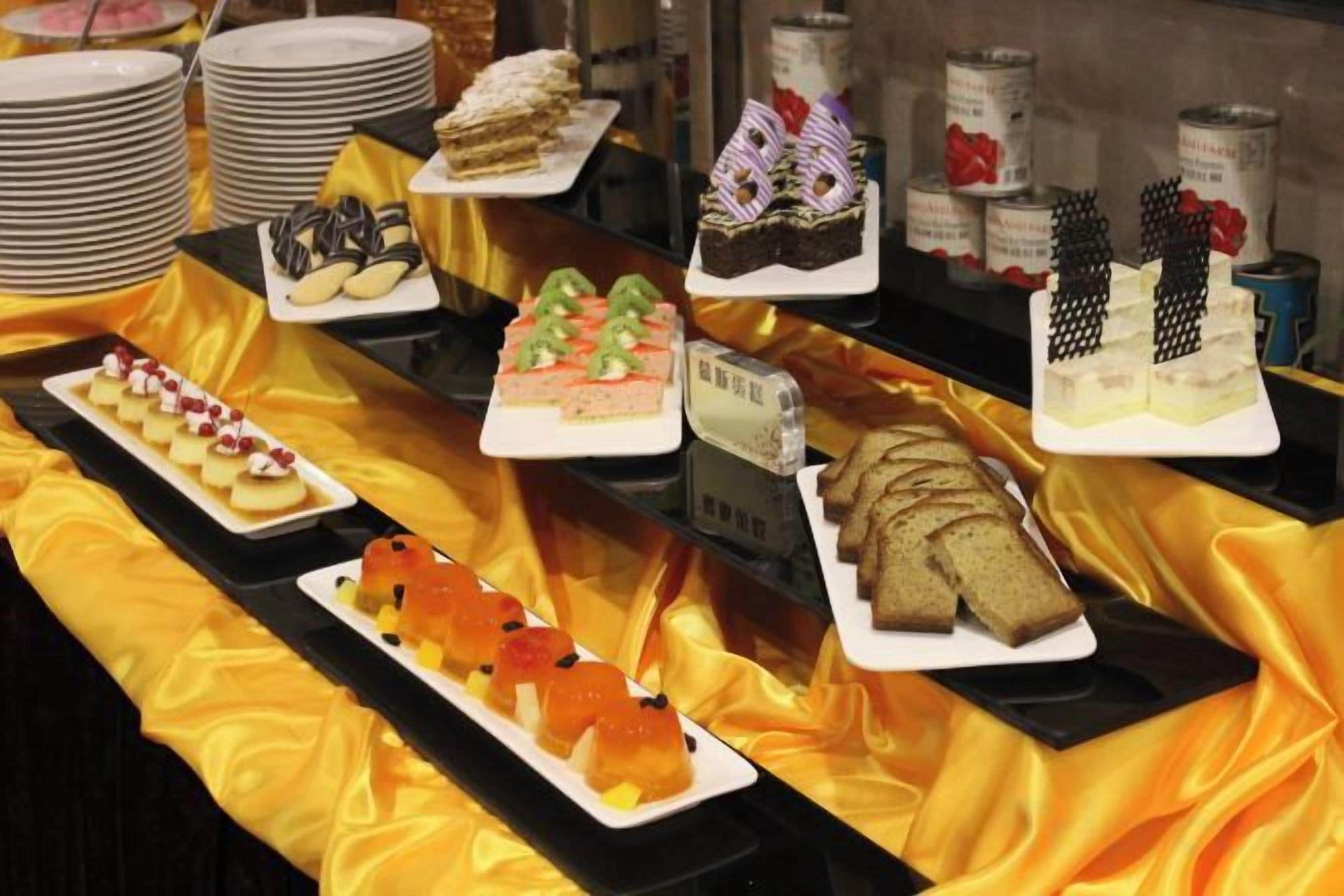 Un bufé con diversos postres y pasteles sobre platos blancos.