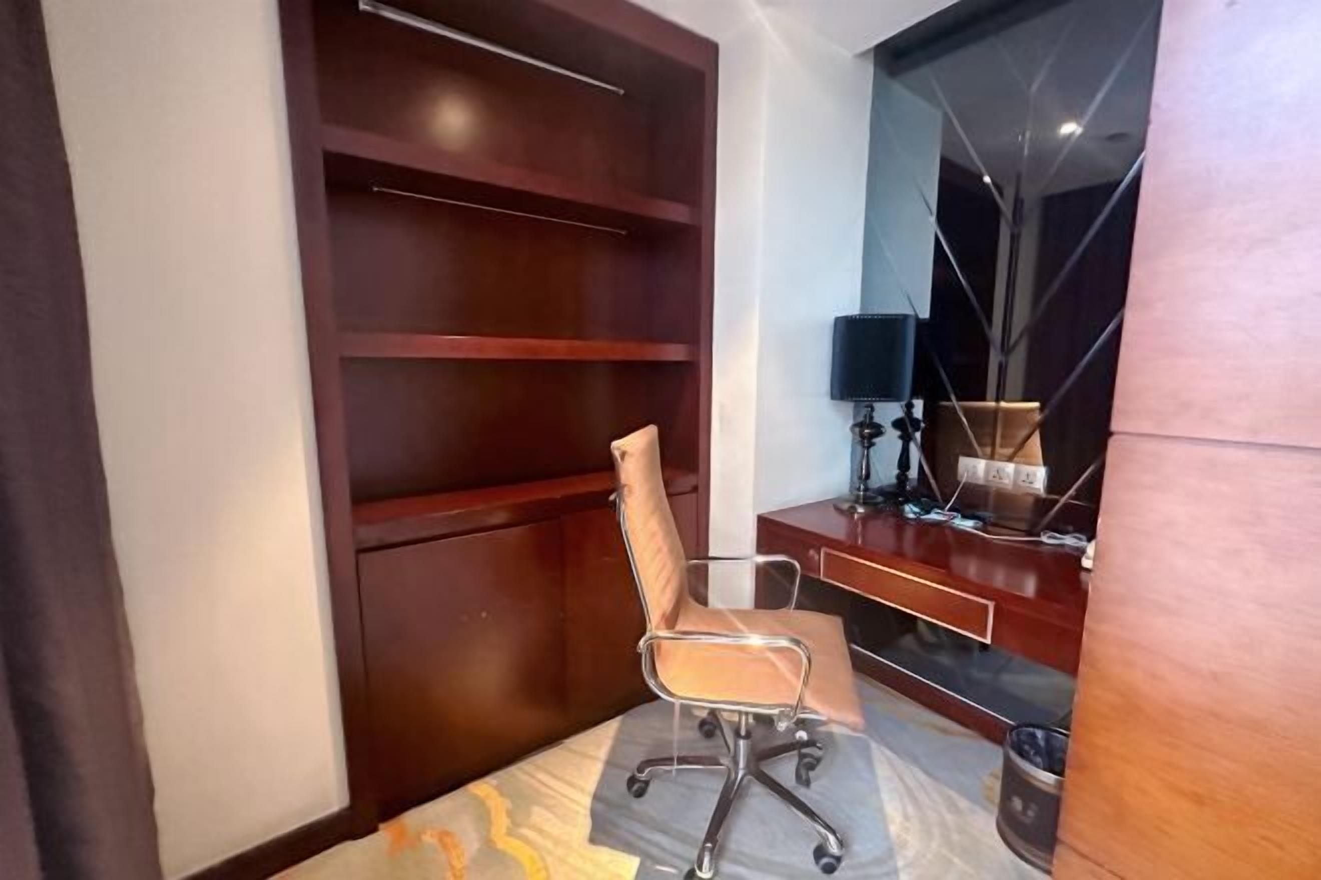 A modern office space with a wooden desk, a chair, and a lamp.