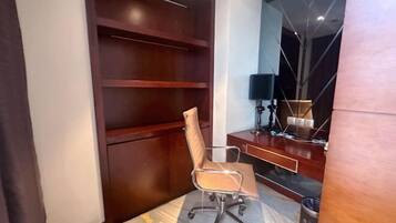 A modern office space with a wooden desk, a chair, and a lamp.