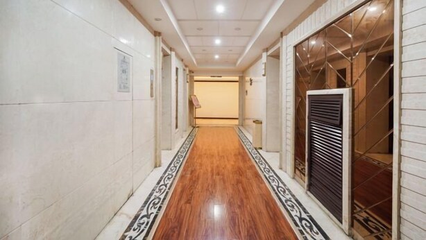 Un couloir doté d’un plancher en bois, de murs carrelés et d’une porte avec une grille en métal.