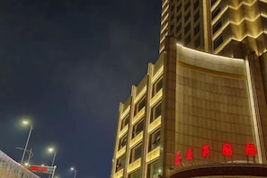 Een meerlaags gebouw met een gebogen gevel en verlichte reclameborden.