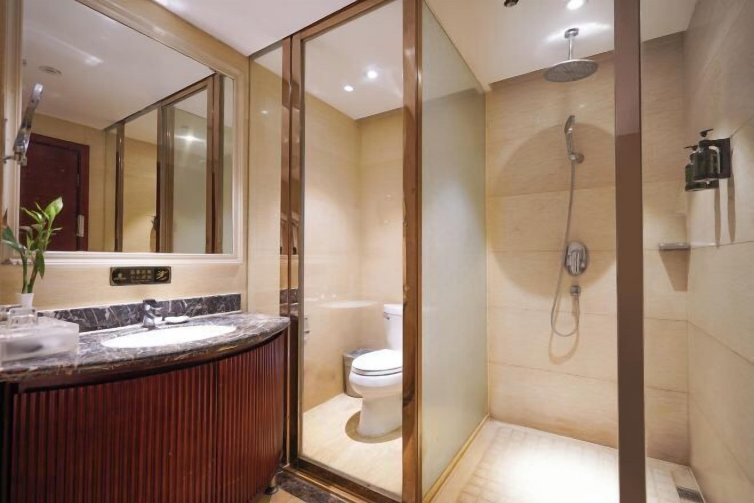 Un baño moderno con ducha de vidrio, lavabo de mármol y retrete.