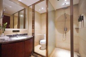 Un baño moderno con ducha de vidrio, lavabo de mármol y retrete.