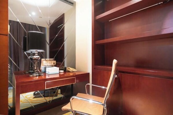 Una habitación de hotel moderna con un escritorio de madera, una silla, una lámpara y un espejo.