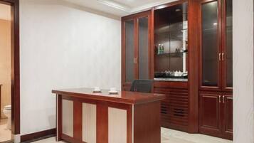 A modern room with a wooden desk and cabinets, a toilet, and a sink.