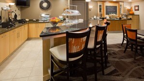A hotel kitchen with a buffet, a clock, and a welcome sign. - AmericInn by Wyndham Waupun (Waupun)