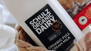 Una botella de leche entera orgánica Schulz Organic Dairy en una cesta tejida.