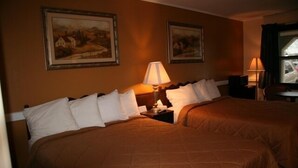 Una habitación de hotel con dos camas, una mesita de noche con lámpara y dos cuadros enmarcados en la pared.