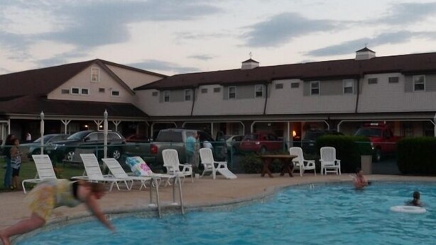 Una piscina con sillones de descanso y un edificio al fondo.