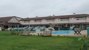 Un hotel de varios pisos con piscina, mobiliario exterior y aparcamiento.