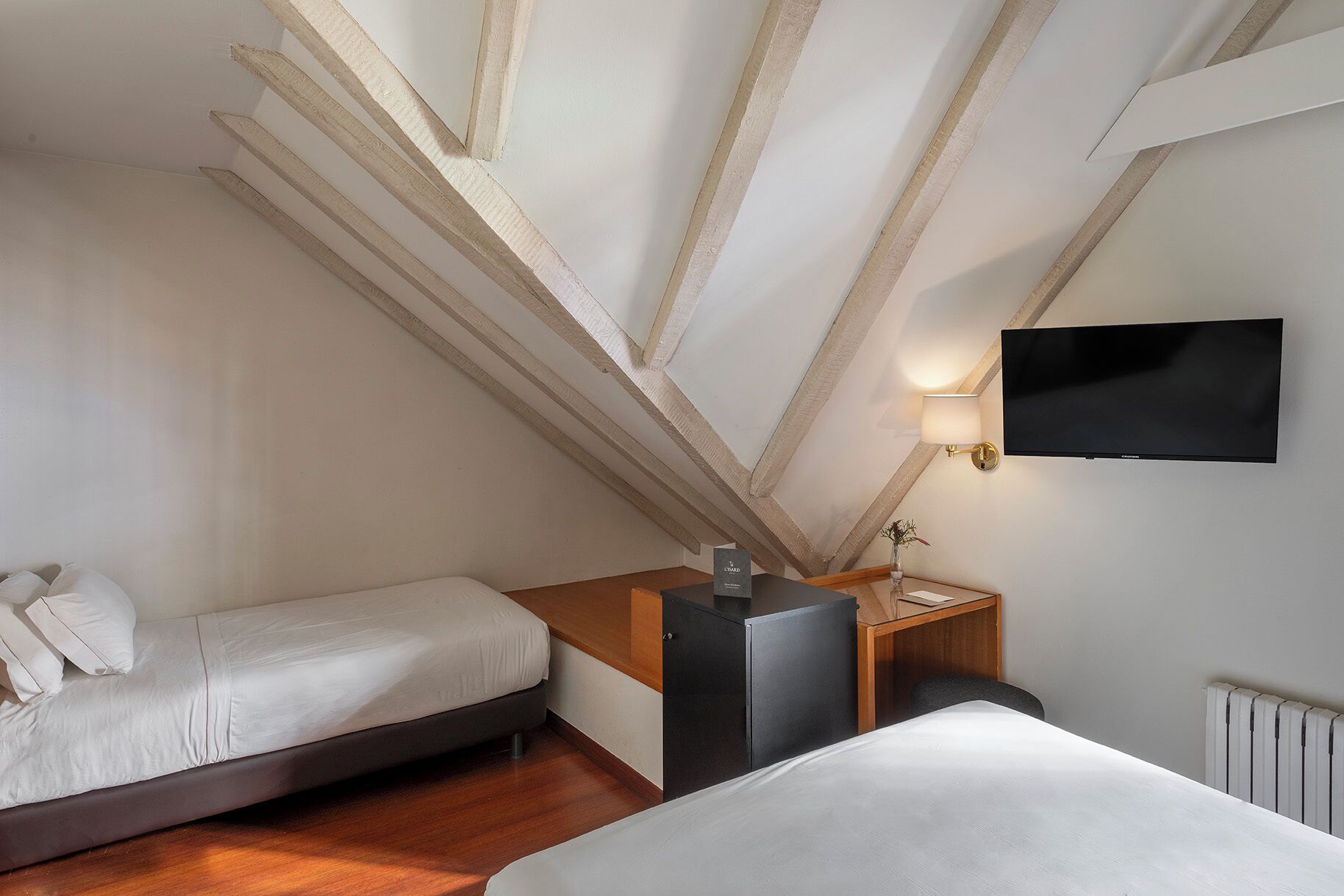 Ein Schlafzimmer mit Bett, Schreibtisch, Fernseher und Heizkörper.