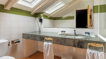 Une salle de bain dotée d’une lucarne, d’un sèche-cheveux, d’un porte-serviettes et d’un lavabo.