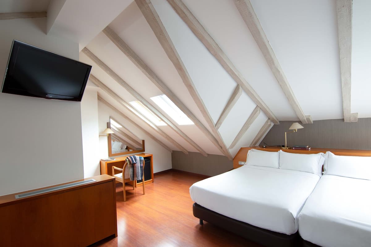 Ein Schlafzimmer mit einem großen Bett, einem Schreibtisch und einem an der Wand montierten Fernseher.