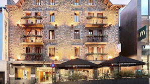 A stone building with multiple balconies, a McDonald's sign, and a hotel café restaurant. - Hotel de l'Isard (Andorra la Vella)